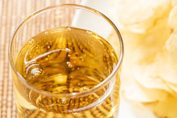 グラスに入れられたハイボール。写真奥にはポテトチップス。
