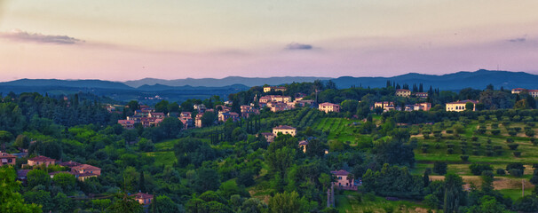 Tuscany rolling hills from Siena, rural misty evening landscape. Green farm fields with cypress trees. Italy 2023