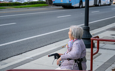 Senior woman sitting on a mobility walker outside the retirement home, taking a rest by the...
