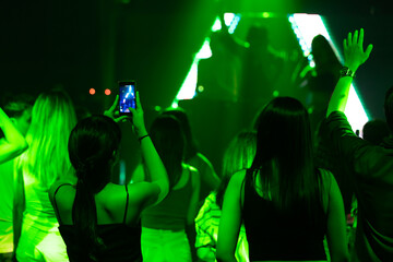 Audience Captures the show with smartphone. music concert live on stage. diverse young people dancing in night club. Nightlife and disco dance party concept. Fun music festival