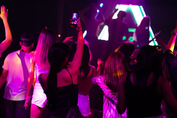 Audience Captures the show with smartphone. music concert live on stage. diverse young people dancing in night club. Nightlife and disco dance party concept. Fun music festival - obrazy, fototapety, plakaty
