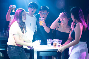 Group of friends having drinks and toasting at the night club party. diverse young people dancing in night club. Nightlife and disco dance party concept. Fun music festival