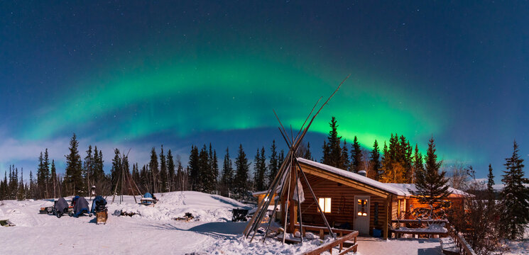 Panorama of Aurora Borealis, Northern Lights, over aboriginal wooden cabin at Yellowknife, Northwest Territories, Canada