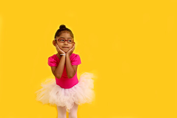 4-year-old brunette Latina girl with eyeglasses dressed in pink leotard and ballerina tutu takes...