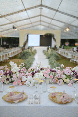 a bunch of flowers arrangement beside the stage catwalk for wedding or engagement decoration outdoors in a sunny day on the fields with tent and a big screen on the wall