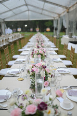 a long straight table setting with bunch of flowers for wedding or engagement decoration outdoors in a sunny day in the field.