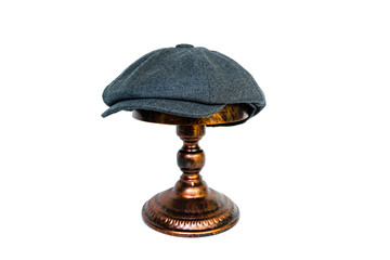 Concept photo catalog of classic newsboy cap with eight panels made of wool and warm dark grey color. Classic hat mounted on a bronze mannequin head on a white studio background