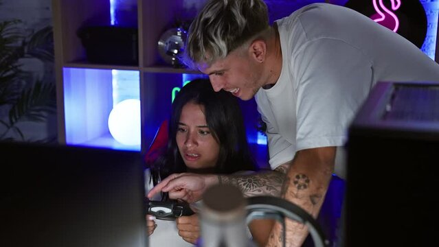 A man and woman focused while gaming together in a neon-lit room at night, conveying companionship and modern entertainment.