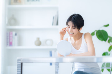 部屋でスキンケアをする若い女性