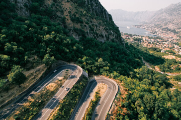 Cars drive along a serpentine road in the mountains above the Bay of Kotor. Montenegro. Drone
