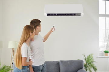Family couple activating, turning on the wall mounted air conditioner. With precision and ease,...
