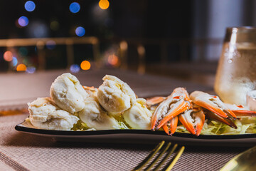 Steamed crab meat and legs on a white plate with seafood dipping sauce.