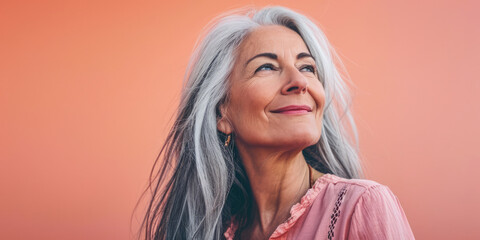 Fototapeta premium Close up of a confident middle aged woman with a peach copyspace background