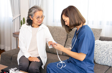 A senior woman giving a health interview to a home visiting nurse and young female nurse measuring...