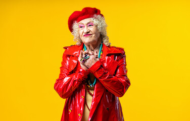 Beautiful senior old woman wearing fancy party clothes acting on a colored background in studio