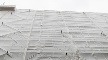 high scaffolding on a building with an empty large white tarpaulin