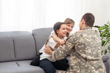  happy positive smiling soldier man in camouflage sitting with his daughter on sofa, looking how his kid grown when he was in army, returning home from war.