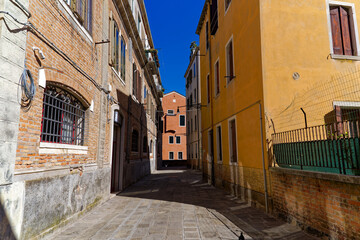 Old town of Italian City of Venice with alley with colorful weathered facades on a summer day. Photo taken August 6th, 2023, Venice, Italy.