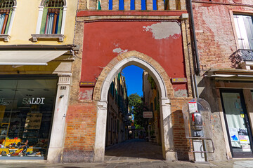 Scenic view of the old town of Venice with red facade and gate with alley and on a sunny summer...