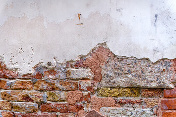 Close-up of weathered brick wall with broken white plaster at the old town of Venice on a sunny summer day. Photo taken August 7th, 2023, Venice, Italy.