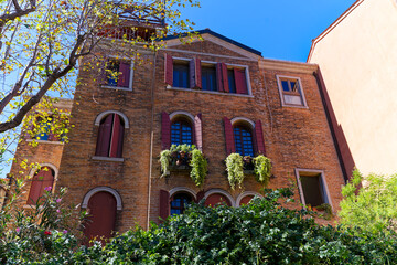 Old town of Italian City of Venice with brick wall facade decorated with plants on a sunny summer day. Photo taken August 7th, 2023, Venice, Italy.