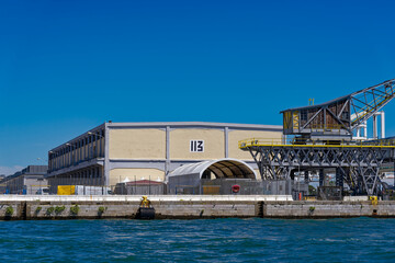 Old town of Italian City of Venice with cargo crane at dock number 113 at canal San Giorgio canal on a sunny summer day. Photo taken August 7th, 2023, Venice, Italy.