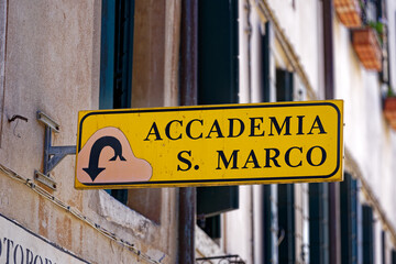 Fototapeta premium Old town of Italian City of Venice with yellow direction sign to art house Accademia and San Marco square on a sunny summer day. Photo taken August 7th, 2023, Venice, Italy.