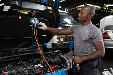 mechanic worker fixing and checking a car air conditioning system in automobile repair shop - obrazy, fototapety, plakaty
