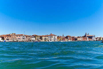 Fototapeta na wymiar Old town of Italian City of Venice with colorful facades of historic houses and church tower seen from Canale san Giorgio on a sunny summer day. Photo taken August 7th, 2023, Venice, Italy.