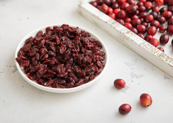 Plate with dried red sweet cranberry with ripe cranberries in wooden box.Macro.