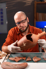 Archaeologist working late at night in the office studying an ancient vase found at an excavation
