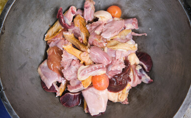 Raw chopped chicken pieces in a pan.