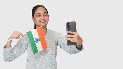 Celebration of 26 January in India, a young Indian girl showed his patriotism, holding with national flag in her left hand and taking a selfie with the tricolor flag, on an isolated white background.