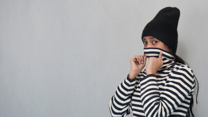 Landscape view of a young Indian girl protecting her face in the winter season by wearing a black...