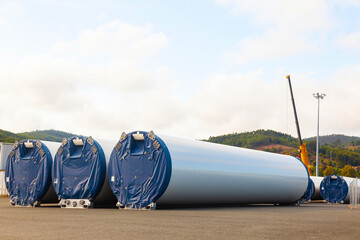 New packaged wind turbine blades lie on the territory of the seaport. - obrazy, fototapety, plakaty