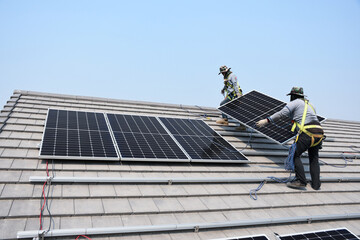 Two technicians are installing solar panels on the roof to use solar energy to power the building.