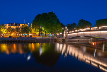 The illuminated Stadsbron bridge over the river Lidan in Lidkoping in the glowing blue hour lighting and colorful reflections