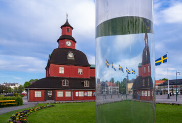 Lidkoping, Sweden - May 28, 2023: Historical red wooden town hall with waving swedish flags in Lidkoping. - obrazy, fototapety, plakaty
