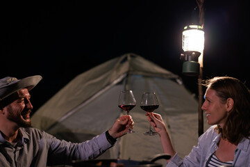 Couples camping and drinking wine in the light at night happily,