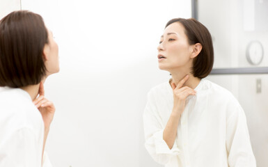 鏡に映る肌を見ている40代日本人女性