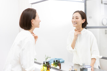 鏡を見ながら喉を触っている40代日本人女性