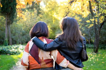 Unrecognizable couple of mother and daughter hugging walking seen from behind