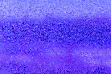 Frost patterns on a window in winter day (violet background)