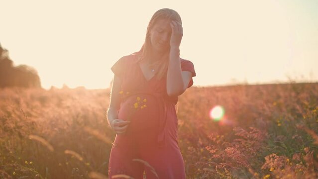 beautiful young pregnant woman on field at sunset - dreamlike looking of a lady in anticipation