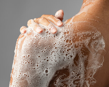 Woman washing soaped her body with a foam