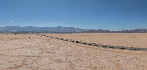 Classic panorama view of an endless straight road running through the barren scenery of the American Southwest. Extreme heat haze on a beautiful hot sunny day with blue sky in summer