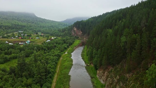 Ural mountains landscape. Aerial view of river flowing among green forest and mountains. Inzer river in Aigir village, Bashkortostan, Russia