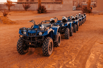 Blue quads stand in a row on the shore of the Sahara desert.