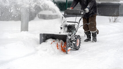 A snow plow removes snow in the yard of the house