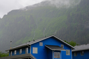 Grey, misty, foggy morning in Juneau Bay, Alaska with small islands channel cruising and houses,...